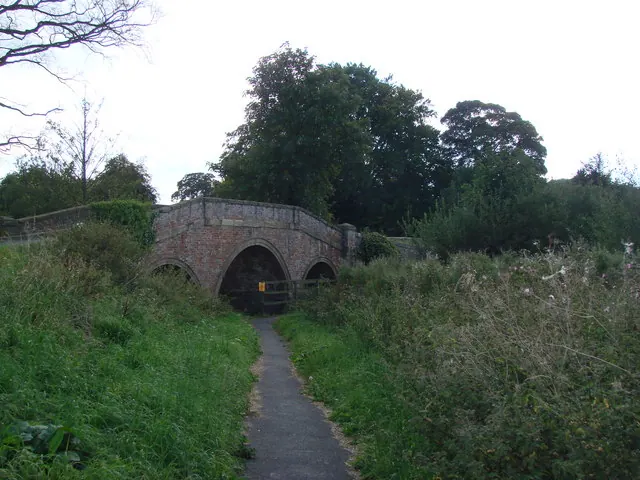 Footpath to the footbridge which crosses the burn alongside the road bridge.